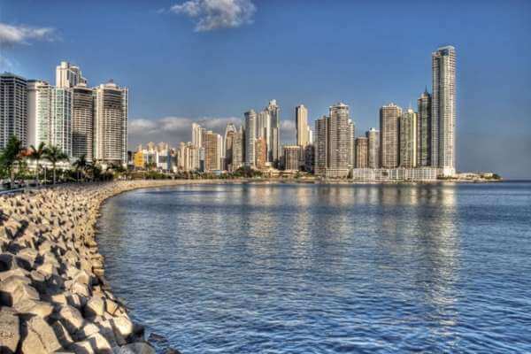 view across panama bay of panama city. Breakwater stones, ocean and buildings on the shore.