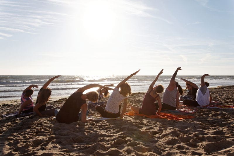 Group practising yoga at the beach. make money in retirement