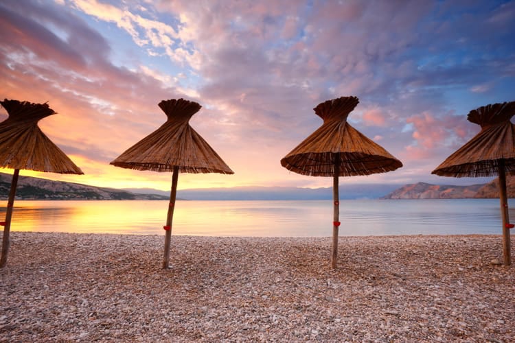 Straw umbrellas on the beach in Baska, Croatia