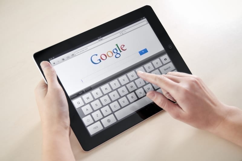 Woman hands holding and touching on Apple iPad2 with Google search web page on a screen.