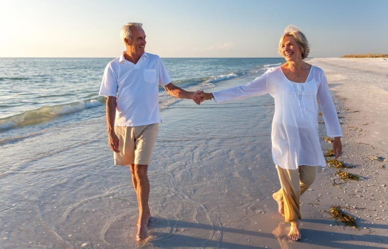 Retired couple walking in a beach.