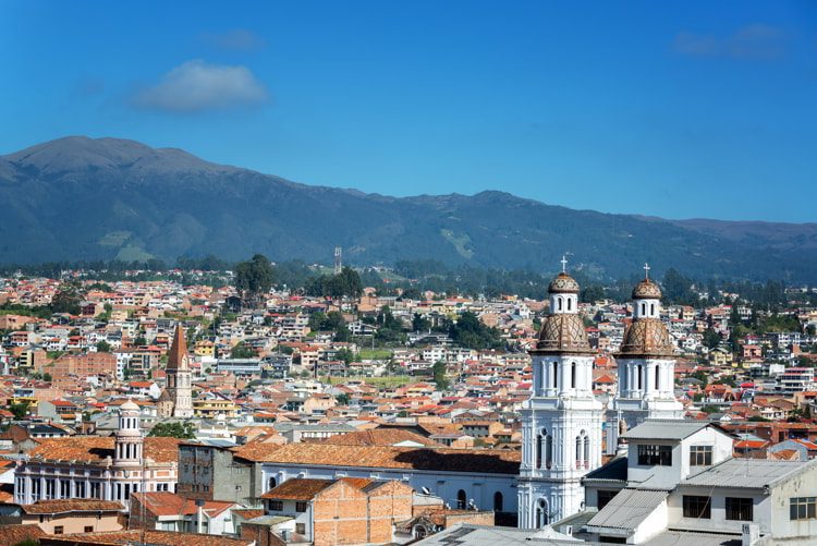 Cityscape of Cuenca, Ecuador with Santo Domingo church visible in the bottom right.