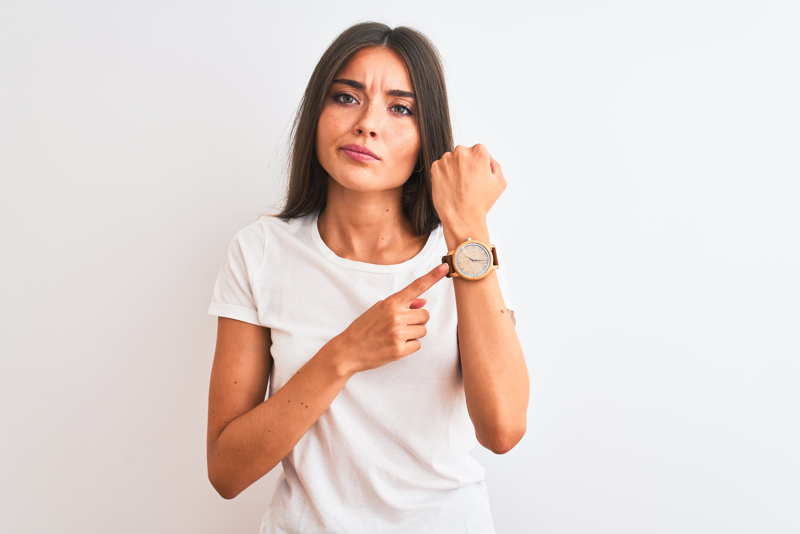 an impatient woman pointing to her watch