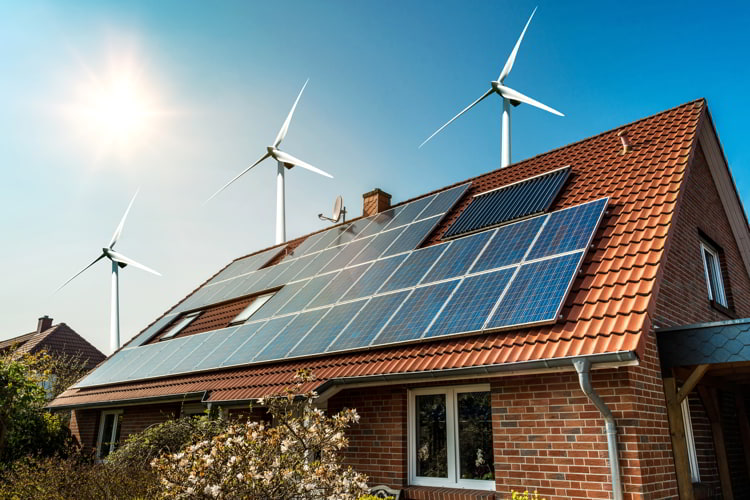 Solar panel on a roof of a house and wind turbines 