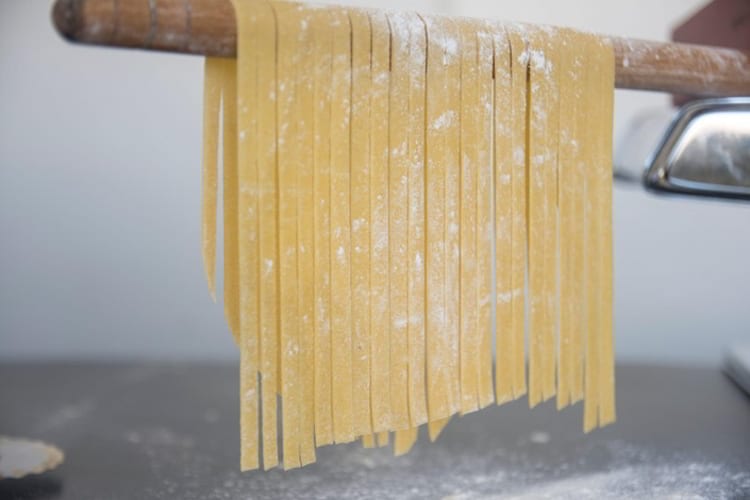 Homemade pasta linguine hanging on wooden stick to dry