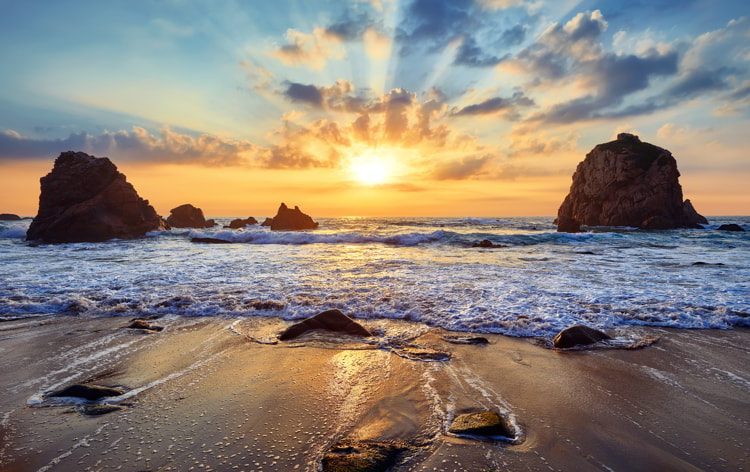 Sand beach among rocks during sunset in Portugal.