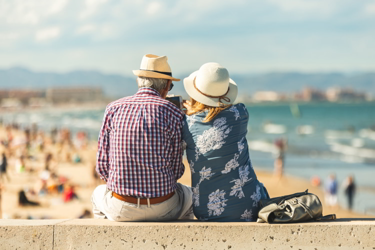 Elderly couple sitting on the wall facing the beach