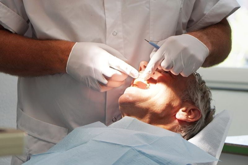 Man at the dentist, having his teeth checked.