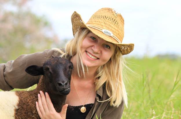 A lady smiling and holding a sheep