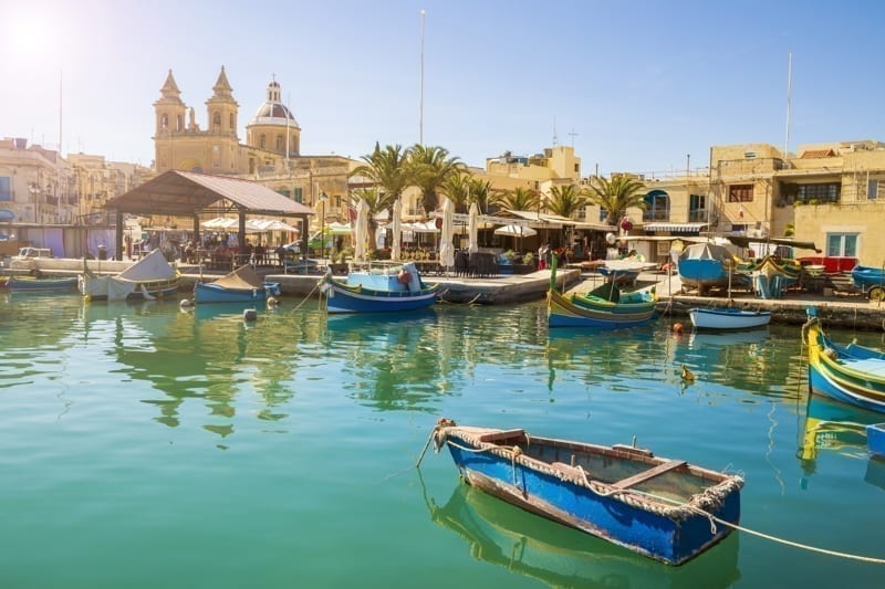  Malta - Marsaxlokk market with traditional colorful Luzzu fishing boats. 