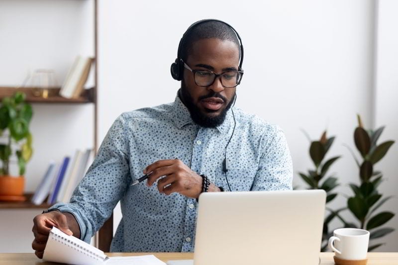 Man sitting at table wearing headphones learn foreign language. 