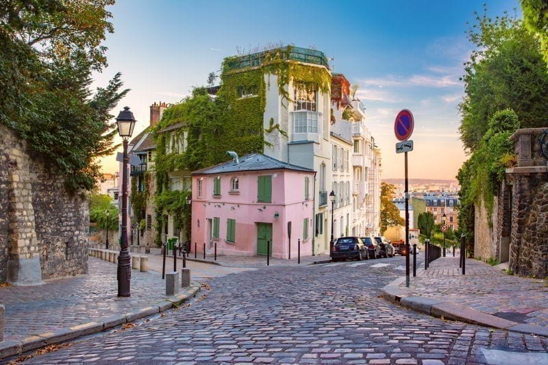 Cozy old street with pink house at the sunny sunrise, quarter Montmartre in Paris, France.