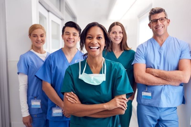 Portrait Of Laughing Medical Team Standing In Hospital Corridor. 