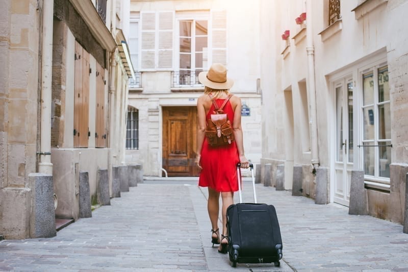 Woman tourist walking with suitcase on the street in European city, tourism in Europe. 