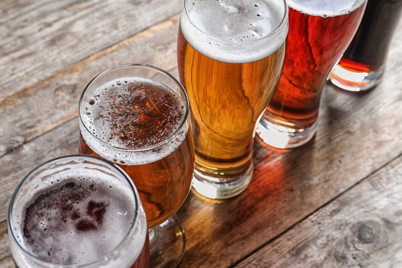 Glasses with different types of cold tasty beer on wooden table