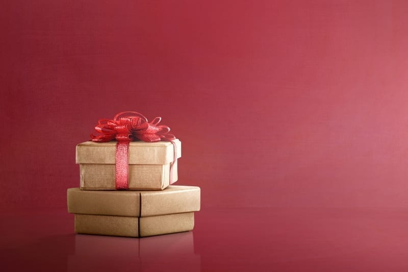 Golden gift box with red ribbon on red background. Boxing Day Concept