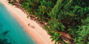 Two people walking on a white sand beach in Dominican Republic. Snowbird Destination