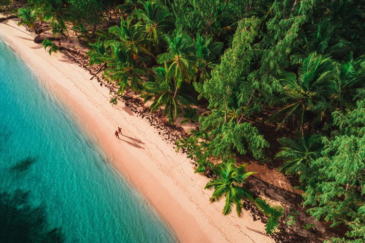 Two people walking on a white sand beach in Dominican Republic