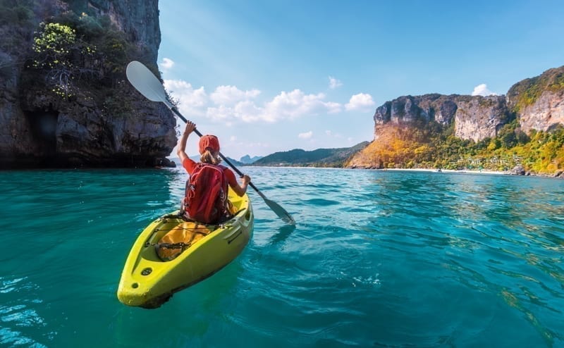 Woman paddles kayak in the tropical sea
