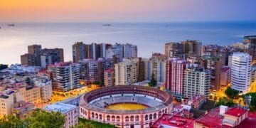 Malaga, Spain at dawn with colorful buildings and the sea in the background.