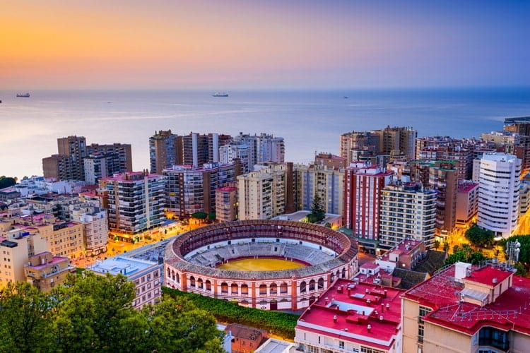 Malaga, Spain at dawn with colorful buildings and the sea in the background.