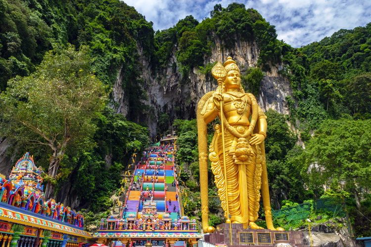 Batu cave in Malaysia with a gold statue of a Hindu god