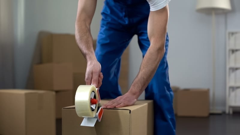 Moving company worker packing cardboard boxes, quality delivery services. move to mexico