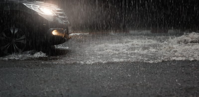 Car with headlights run through flood water after hard rain fall. property overseas