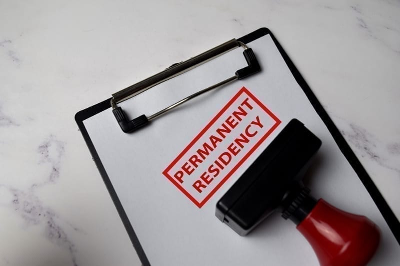 Red Handle Rubber Stamper and Permanent Residency text isolated on White Background.