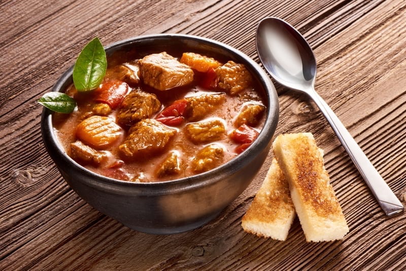 Beef stew with herbs on wooden background. 