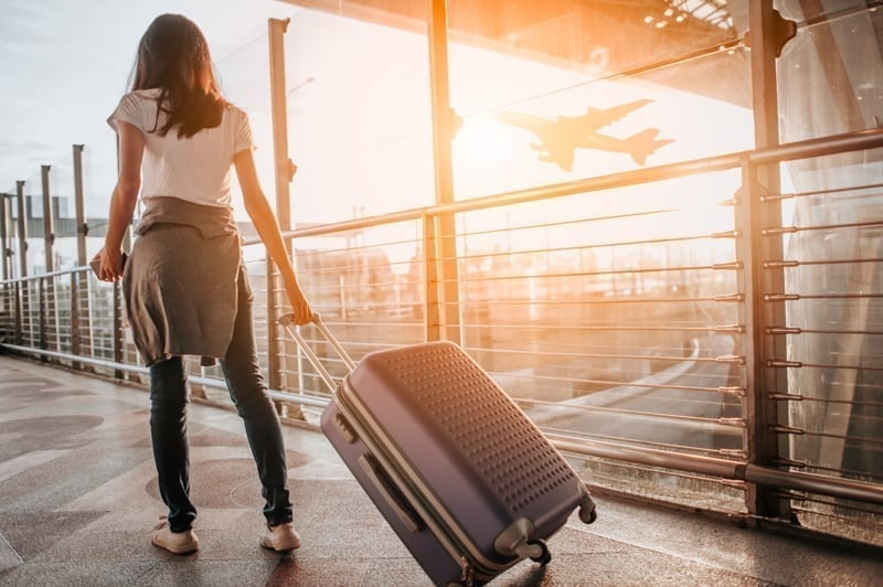 Young woman pulling suitcase in airport terminal