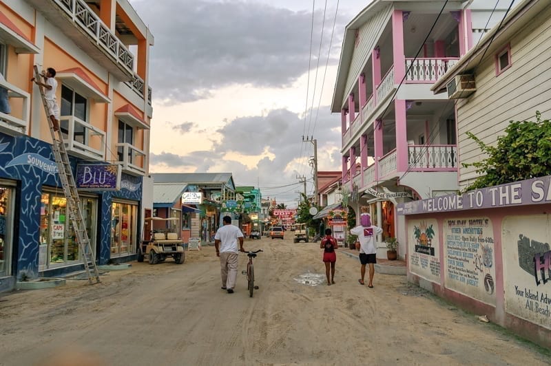 People walk on dirt street in downtown San Pedro island, Belize.