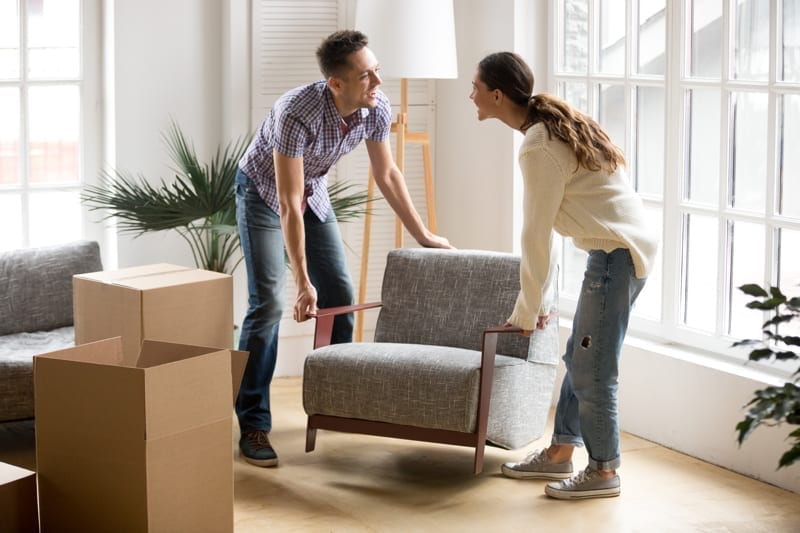 Couple carrying modern chair together 