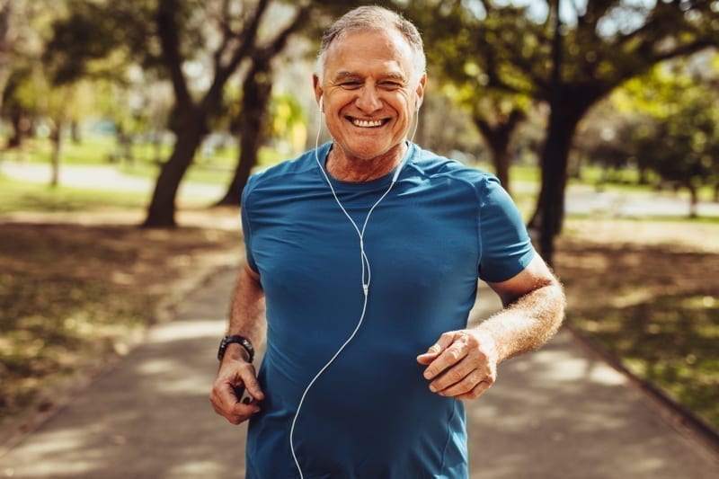 Portrait of a senior man in fitness wear running in a park. 