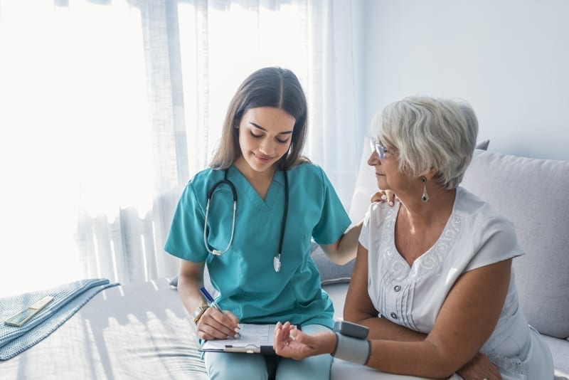 Nurse doing blood pressure monitoring for senior woman.