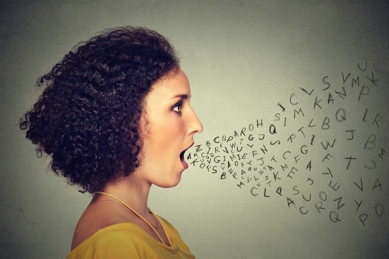 Woman talking with alphabet letters coming out of her mouth.