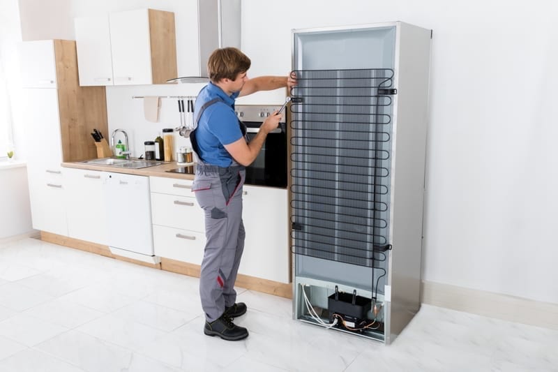 Serviceman Working On Fridge