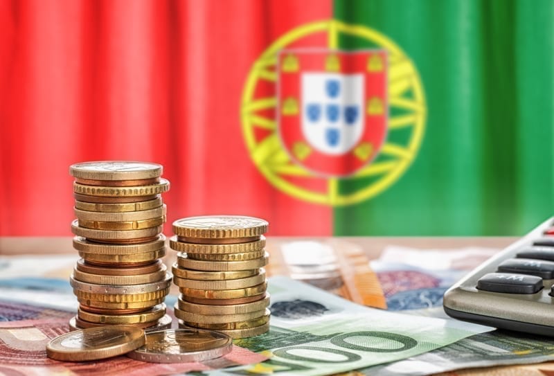 Euro banknotes and coins in front of the national flag of Portugal