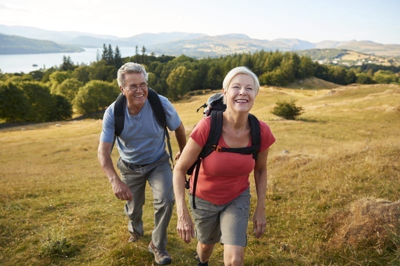 Senior Couple climbing hill on hike. 