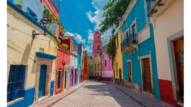 A vibrant colonial street featuring brightly painted buildings, charming architecture, and a historic church in the heart of a cultural city.
