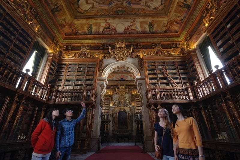 People visiting Coimbra University's 18th century baroque library Biblioteca Joanina in Coimbra, Portugal