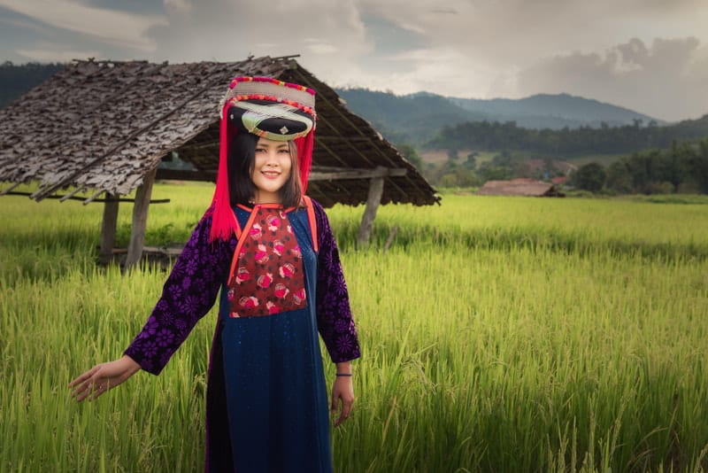 Portrait of Lisu woman in traditional dress and jewelry costume in rice fields in Thailand