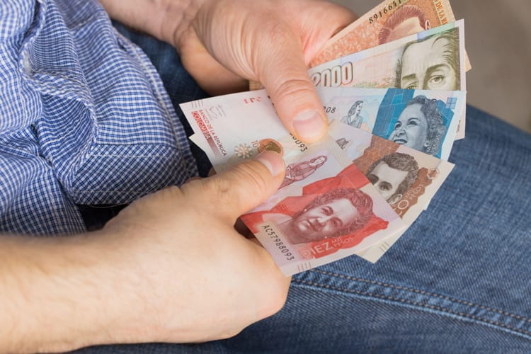 A man holding a bundle of Colombian pesos in his hands