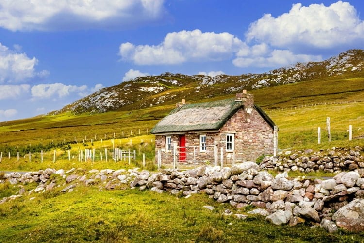 Traditional Irish thatched cottage and stone wall or fence on Achill Island in County Mayo Ireland