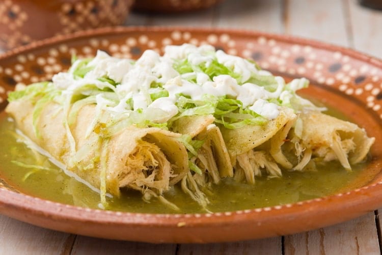 Mexican green chicken enchiladas served on a traditional clay plate