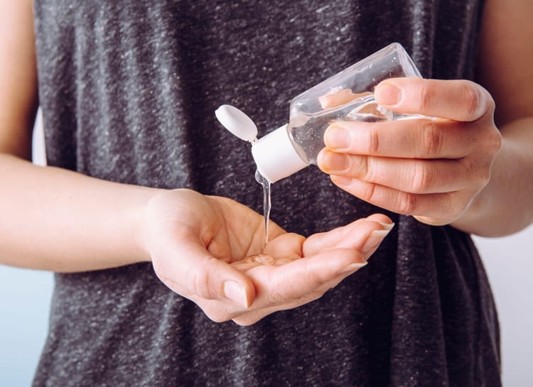 Close up view of person using small portable antibacterial hand sanitizer on hands