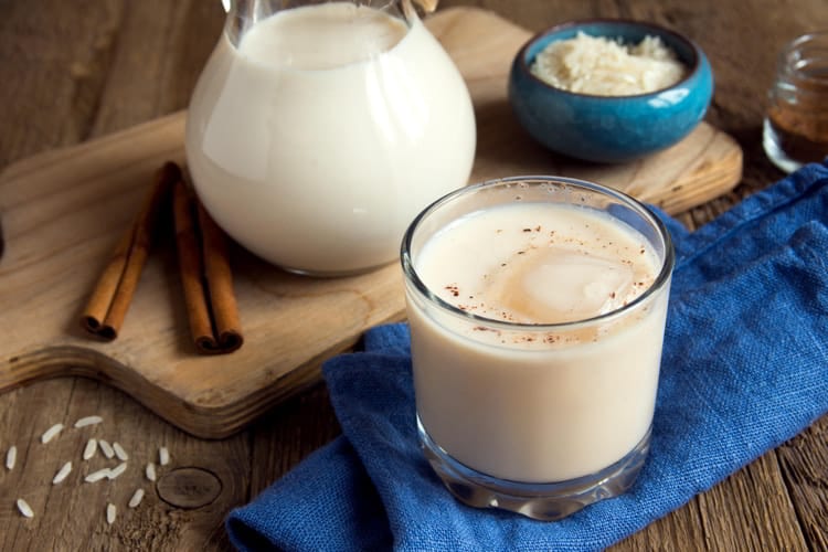 Horchata with cinnamon and ice in glass over rustic wooden table