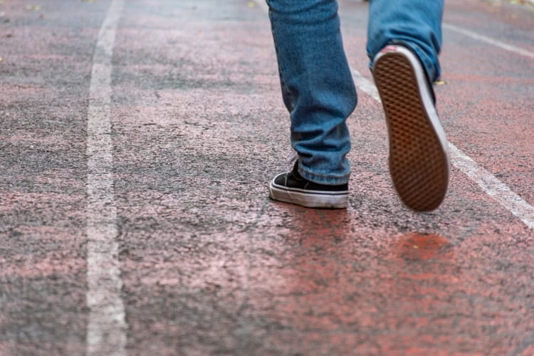 Man wearing jeans and sneaker shoes walking in empty street