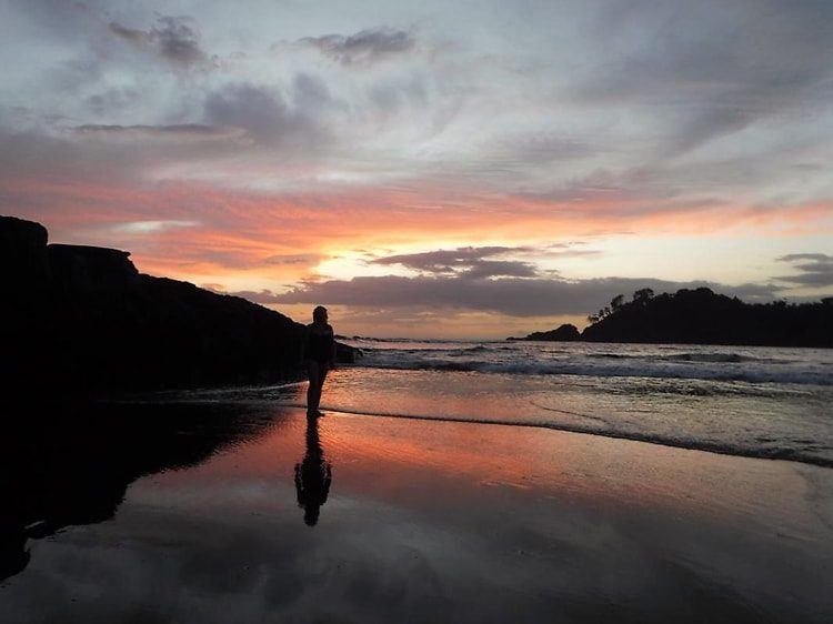 los-islotes-sunset A person standing on a beach during sunset in Los Islotes, Panama