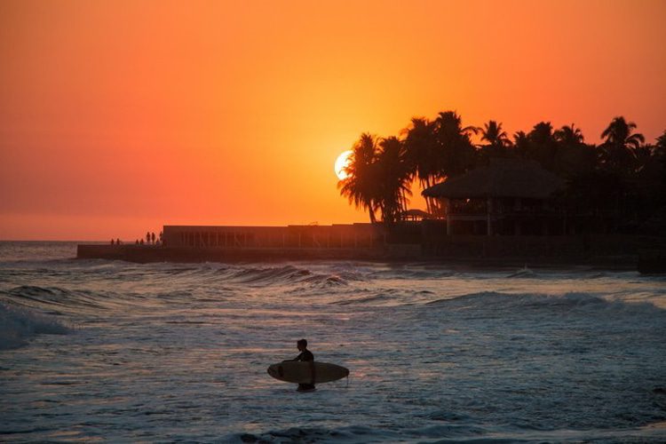 Surfer in the water during a sunset at Playa el Tunco, El Salvador